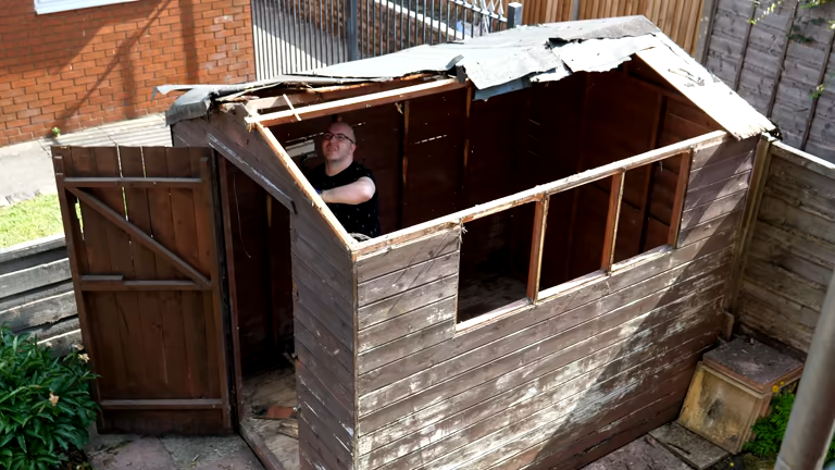 Timber backyard shed mid-demolition with roof and walls partially dismantled by a tradie
